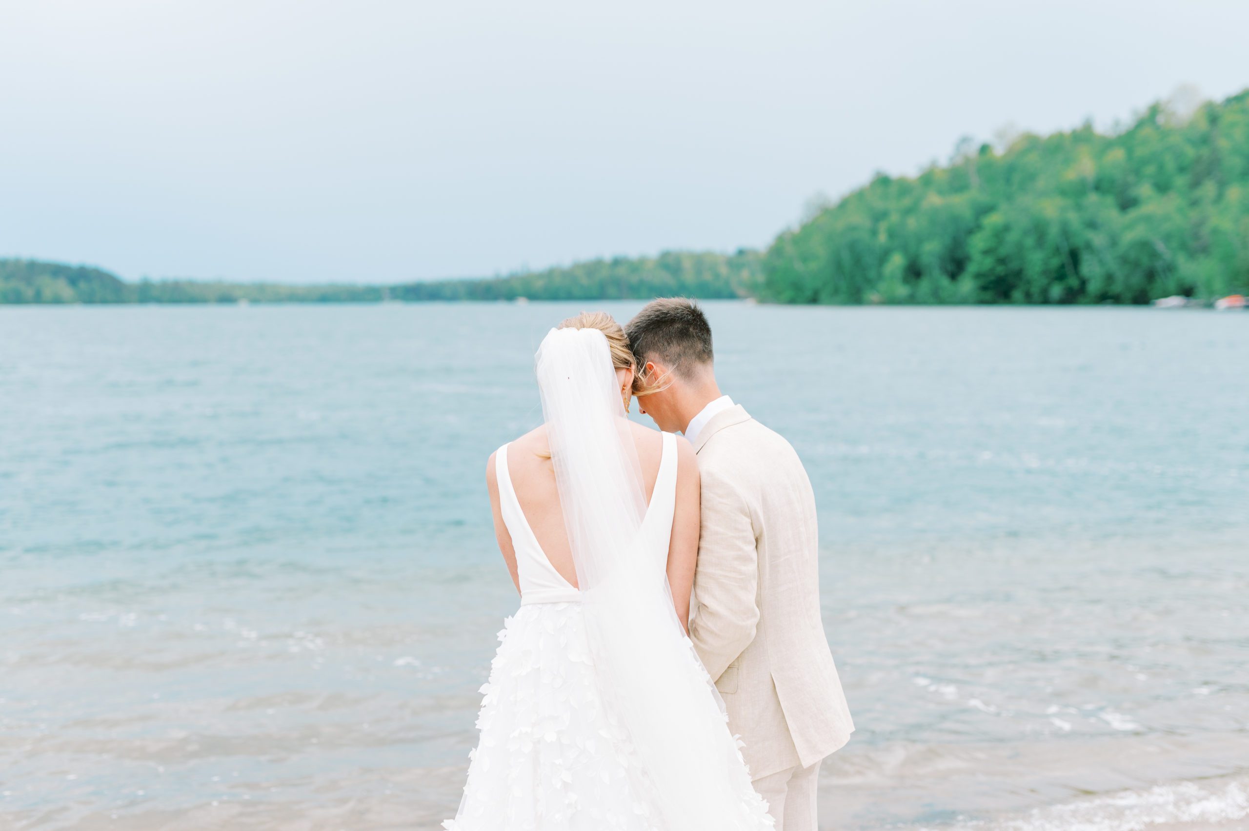 bride and groom pray with ocean in the back