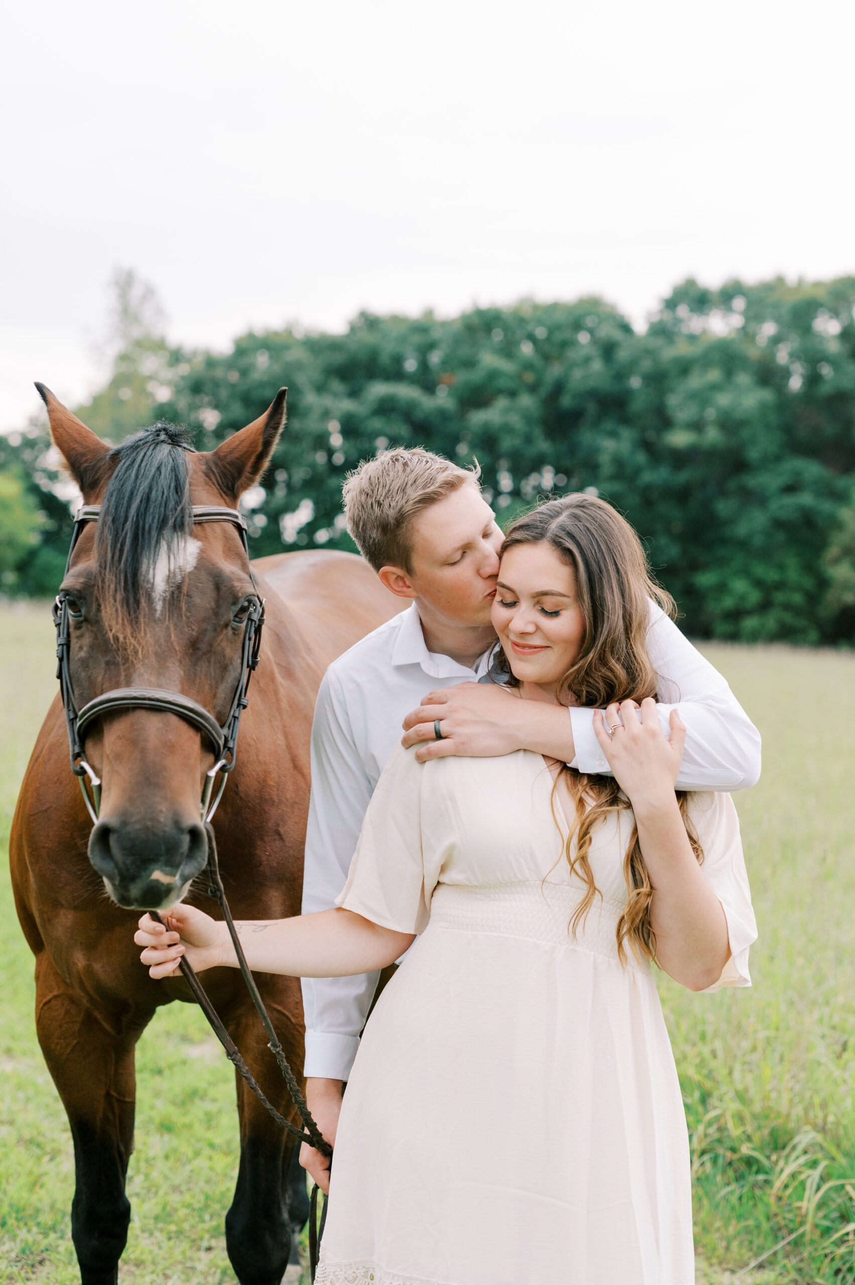 Engagement session with couple and a horse in a grassy field