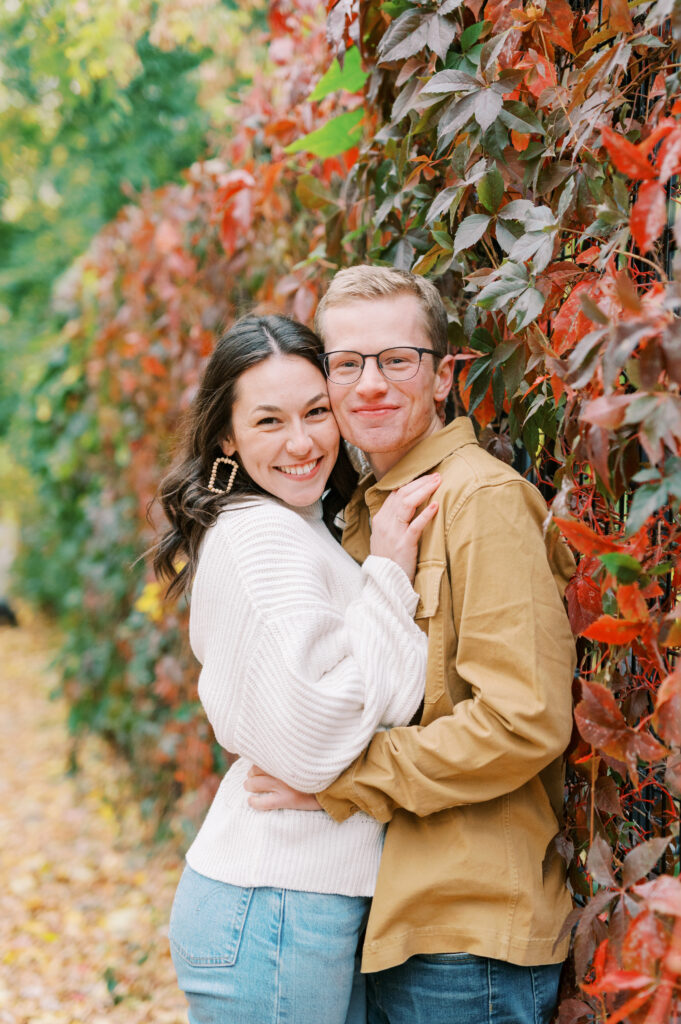 Engagement session in the fall with couple standing together smiling at the camera