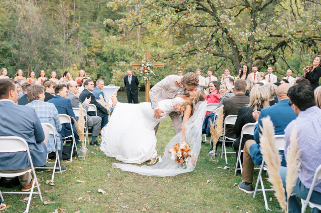 Couple doing a "dip kiss" down the aisle